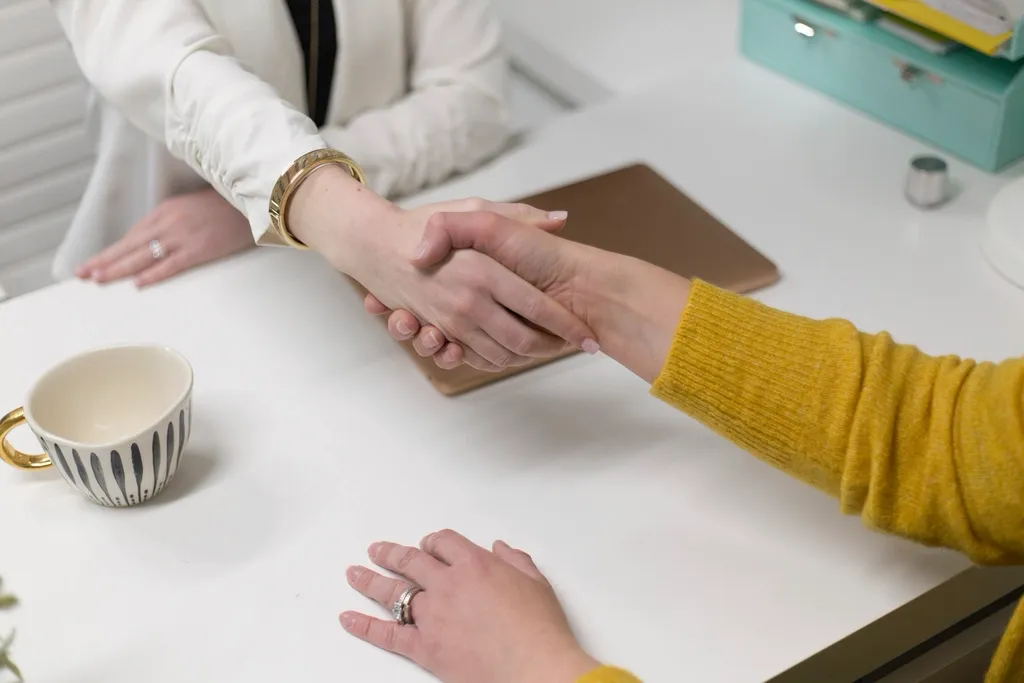 Poignée de main entre deux personnes autour d’une table